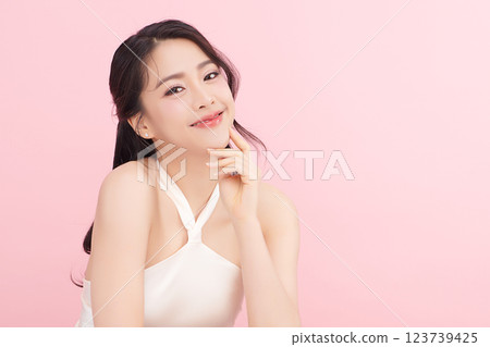 A beautiful young Asian woman with clean, fresh skin against a pink background. Skincare, facial treatment, cosmetology, beauty, and spa. An elegant portrait of an Asian woman. 123739425