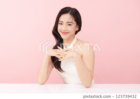 A beautiful young Asian woman with clean, fresh skin against a pink background. Skincare, facial treatment, cosmetology, beauty, and spa. An elegant portrait of an Asian woman. 123739432