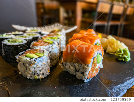 Japanese sushi rolls with salmon, avocado and cream cheese on black background, close-up. Japanese sushi rolls with salmon, avocado and cream cheese on black background, close-up. 123739599