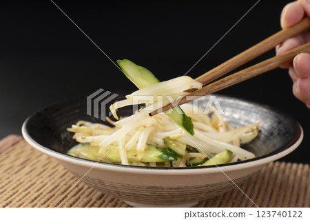 Picking up bean sprout and cucumber namul with chopsticks 123740122