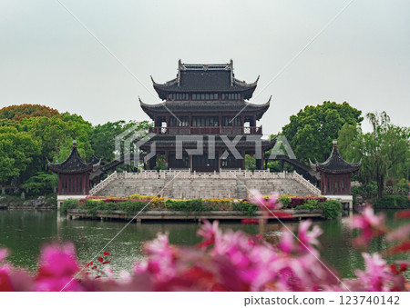 A stunning pavilion showcases classic Chinese architecture, surrounded by lush greenery and vibrant pink flowers 123740142