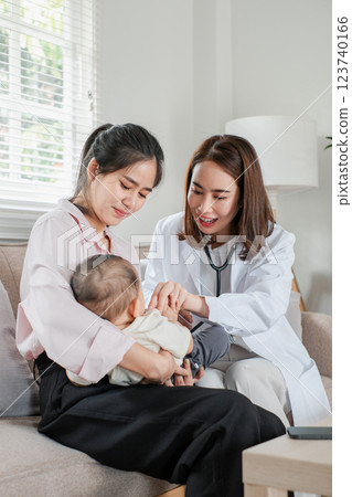 Pediatrician checks baby's health while mother watches in cozy living room, highlighting home healthcare. 123740166
