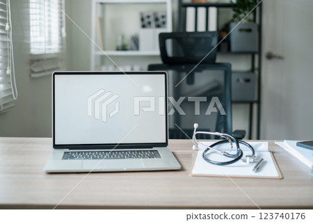 A clean and modern office desk setup featuring a laptop and stethoscope, ideal for medical or professional themes. 123740176