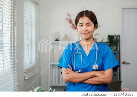 A confident female nurse in blue scrubs with a stethoscope, standing in a modern medical office setting. A confident female nurse in blue scrubs with a stethoscope, standing in a modern medical office setting. 123740192