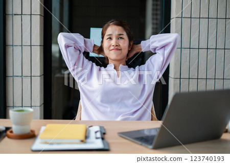 A woman in a white blouse relaxes at her desk with a laptop and coffee, embodying a calm and productive work environment. A woman in a white blouse relaxes at her desk with a laptop and coffee, embodying a calm and productive work environment. 123740193