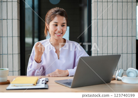 Smiling woman participating in an online meeting, sitting at a desk with a laptop and headphones, showcasing remote work lifestyle. Smiling woman participating in an online meeting, sitting at a desk with a laptop and headphones, showcasing remote work lifestyle. 123740199
