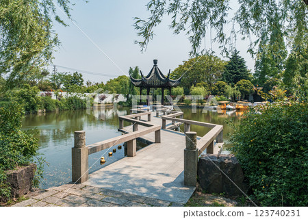 Serene view of a traditional pavilion beside a tranquil lake surrounded by lush greenery Serene view of a traditional pavilion beside a tranquil lake surrounded by lush greenery 123740231