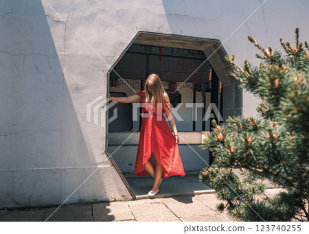 Young woman wearing a flowing red dress poses elegantly in a stone arch in traditional Chinese garden. Young woman wearing a flowing red dress poses elegantly in a stone arch in traditional Chinese garden. 123740255