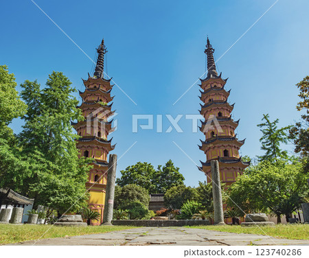 Majestic twin pagodas surrounded by lush greenery under bright blue sky in historical site of Suzhou, China. Majestic twin pagodas surrounded by lush greenery under bright blue sky in historical site of Suzhou, China. 123740286