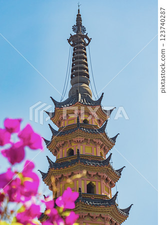 Colorful pagoda surrounded by vibrant flowers in sunlight captures serene beauty of the garden during daytime Colorful pagoda surrounded by vibrant flowers in sunlight captures serene beauty of the garden during daytime 123740287