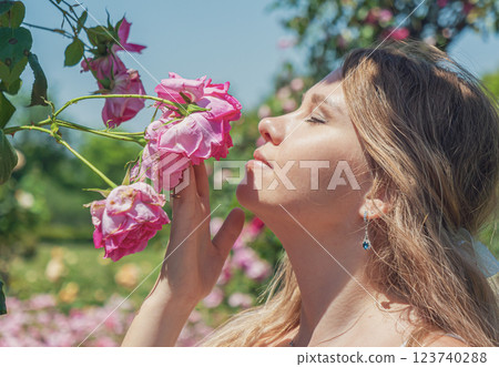Young woman enjoys a sunny day among blooming roses in a vibrant garden setting Young woman enjoys a sunny day among blooming roses in a vibrant garden setting 123740288