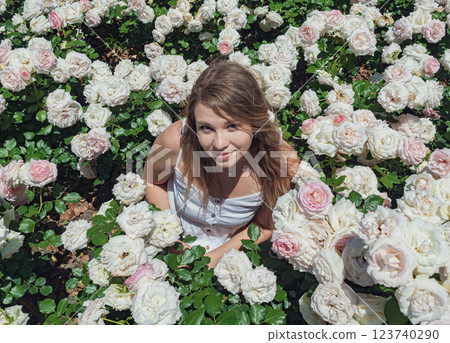Young woman enjoys a sunny day among blooming roses in a vibrant garden setting Young woman enjoys a sunny day among blooming roses in a vibrant garden setting 123740290