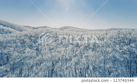 Aerial view of a snow-covered mountain landscape under clear blue sky in winter season 123740344