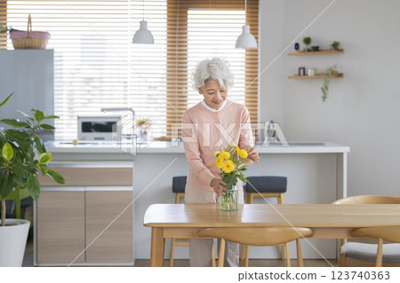 老年婦女用鮮花裝飾家中的餐桌 123740363