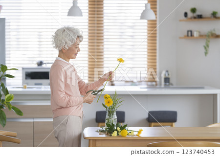 Senior woman decorating the dining table at home with flowers 123740453
