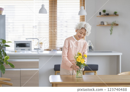 Senior woman decorating the dining table at home with flowers Senior woman decorating the dining table at home with flowers 123740488