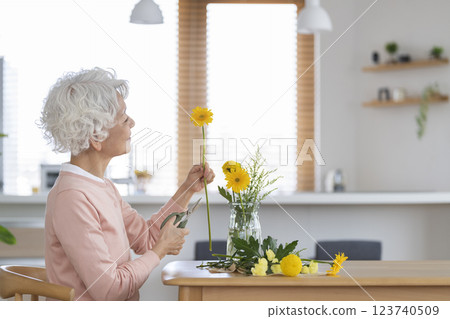 Senior woman decorating the dining table at home with flowers Senior woman decorating the dining table at home with flowers 123740509