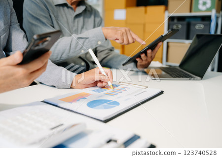 Business documents on office table with smart phone and laptop and two colleagues discussing data 123740528