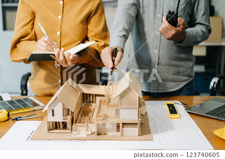Engineer desk with object paper and tablet with blurry engineer teamwork hardworking Engineer desk with object paper and tablet with blurry engineer teamwork hardworking 123740605