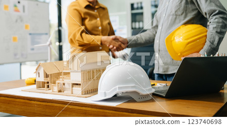 Construction team shake hands greeting start new project plan behind yellow helmet on desk in Construction team shake hands greeting start new project plan behind yellow helmet on desk in 123740698