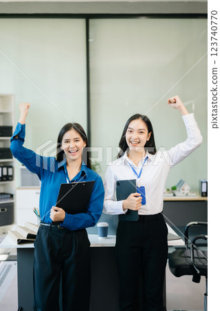 Professional women smiling confidently, collaborating with a tablet and clipboard in a modern office. Professional women smiling confidently, collaborating with a tablet and clipboard in a modern office. 123740770