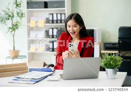 Beautiful woman typing on tablet and laptop while sitting at the working white table 123740834