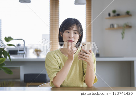 一名 30 多歲的女性一臉苦惱地盯著智慧型手機 123741420