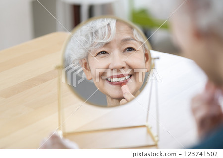 一位老年婦女在鏡子前化妝 123741502