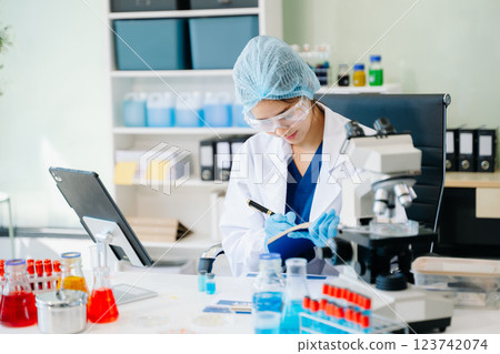 female scientist working with micro pipettes analyzing biochemical female scientist working with micro pipettes analyzing biochemical 123742074