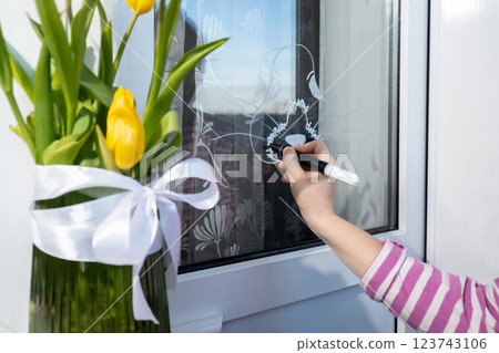 Zero cost responsible holiday decor economically driven. Female hand painting Easter bunny rabbit on window glass indoor at home. Affordable alternative Easter springtime seasonal tradition ideas 123743106