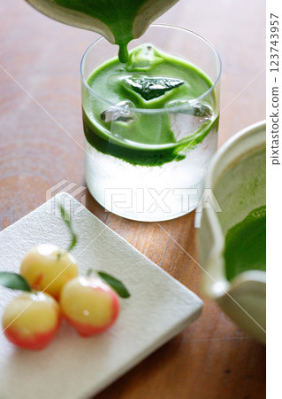 fresh matcha tea, green tea pouring on a glass of coconut water and colorful peach fruit shape Plating balls, Thailand style dessert on wooden table. fresh matcha tea, green tea pouring on a glass of coconut water and colorful peach fruit shape Plating balls, Thailand style dessert on wooden table. 123743957