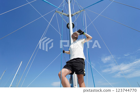 Male captain stands proudly on a sailboat enjoying the moment Male captain stands proudly on a sailboat enjoying the moment 123744770