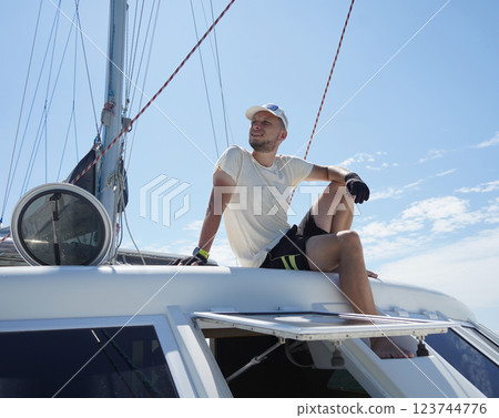 A man is calmly sitting on the deck of a beautiful sailboat 123744776