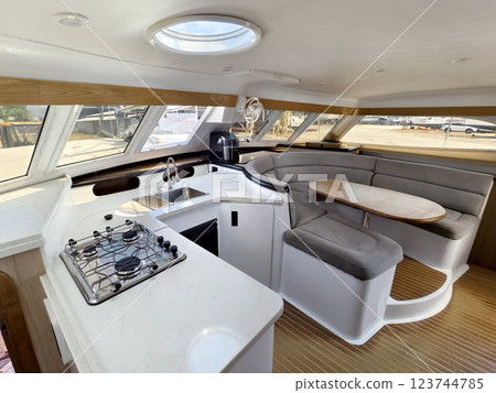 A cozy living room and kitchen featuring a stylish curved couch and a table located on sailing boat 123744785