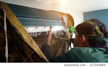 The worker cleans and repairs the air conditioner to ensure it operates properly The worker cleans and repairs the air conditioner to ensure it operates properly 123744860