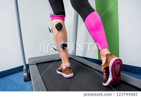 Young sports woman with electrostimulator on the muscles of the legs. Young sports woman with electrostimulator on the muscles of the legs. 123744862