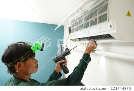 The worker cleans and repairs the air conditioner to ensure it operates properly The worker cleans and repairs the air conditioner to ensure it operates properly 123744870