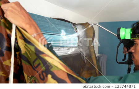 The worker cleans and repairs the air conditioner to ensure it operates properly The worker cleans and repairs the air conditioner to ensure it operates properly 123744871