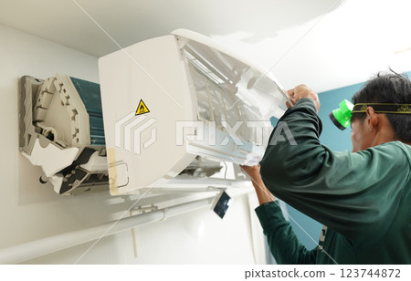 The worker cleans and repairs the air conditioner to ensure it operates properly 123744872