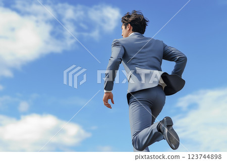 一位身著西裝的年輕男商人在藍天上奔跑 一位身著西裝的年輕男商人在藍天上奔跑 123744898