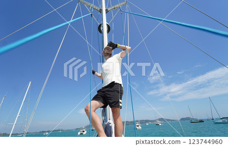 Male captain stands proudly on a sailboat enjoying the moment 123744960