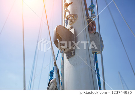 Tall sturdy mast of a sailboat stands out vividly against the bright blue sky. 123744980