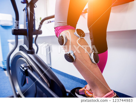 Young sports woman with electrostimulator on the muscles of the legs.  123744983