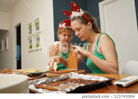 Mother and daughter at the table cooking gingerbread house for Christmas Mother and daughter at the table cooking gingerbread house for Christmas 123745004