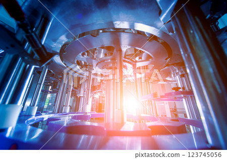 Automatic filling machine pours water into plastic PET bottles. 123745056