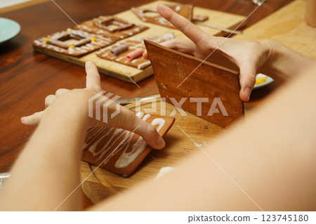 Mother and daughter at the table cooking gingerbread house for Christmas 123745180