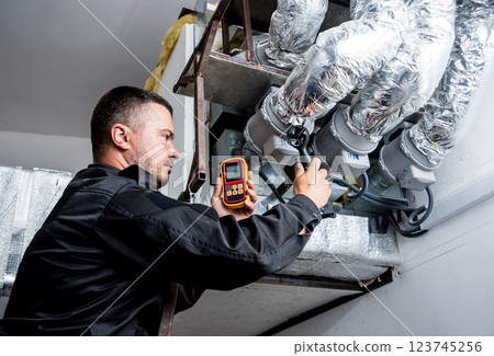 Technician use hand-held anemometer measuring air flowing measurement. 123745256