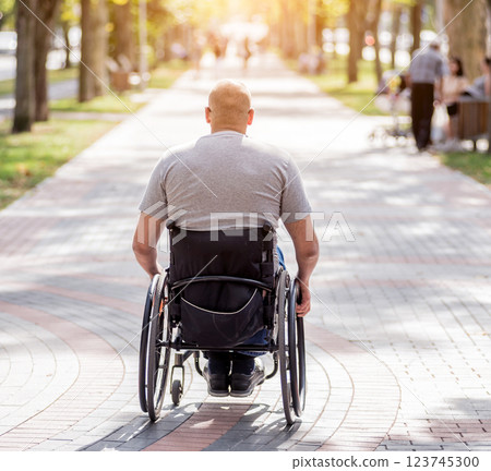 Handicapped man in wheelchair walk at the park alley Handicapped man in wheelchair walk at the park alley 123745300