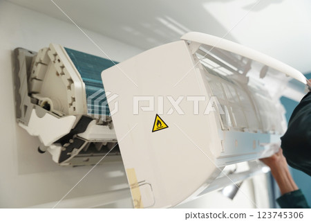 The worker cleans and repairs the air conditioner to ensure it operates properly The worker cleans and repairs the air conditioner to ensure it operates properly 123745306