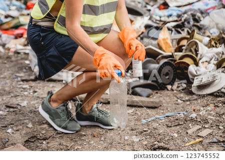Woman volunteer helps clean the field of plastic garbage. Woman volunteer helps clean the field of plastic garbage. 123745552